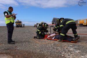 Photo of three firemen and an observer attending to an actor playing a survivor on an emergency exercise at St Helena Airport